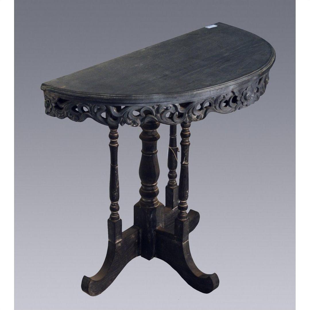 Brown wood antique demi lune table with carved trim and four turned legs, set against a plain gray background.
