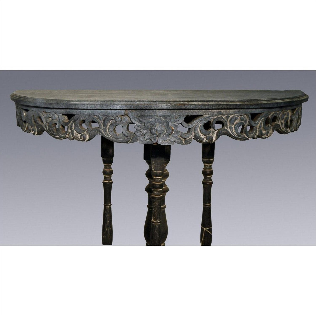 Dark wood antique demi lune table with carved floral accents and three turned legs, shown on a plain background.