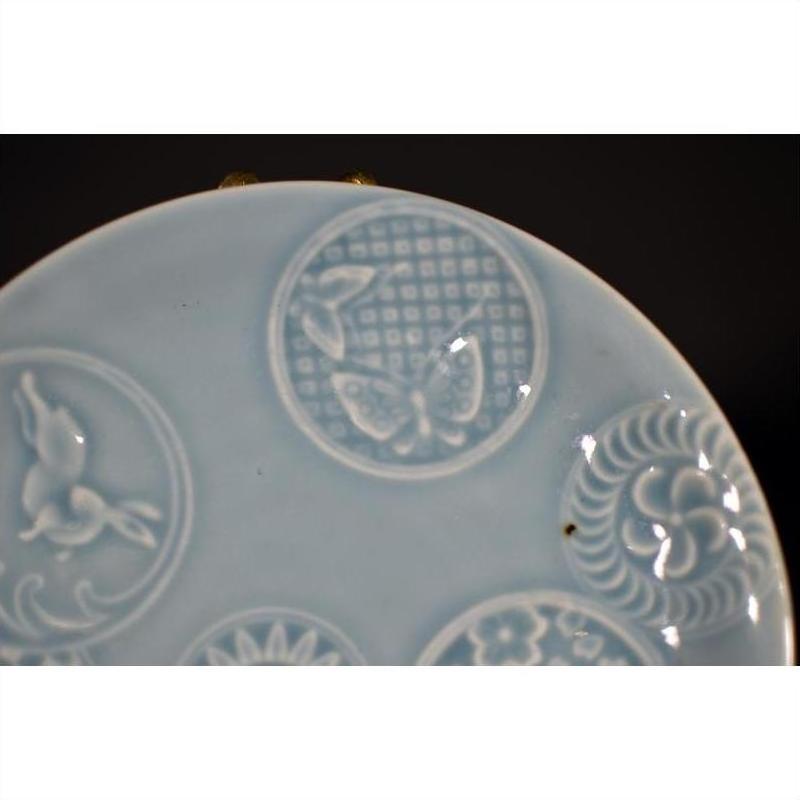Close-up of white porcelain plate with embossed butterfly and floral patterns, antique Chinese design.