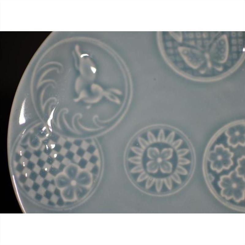 Close-up of white embossed Chinese porcelain plate with rabbit, butterfly, and floral designs.