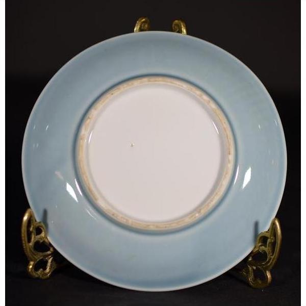 Light blue embossed Chinese porcelain plate with white center on gold stand, close-up.