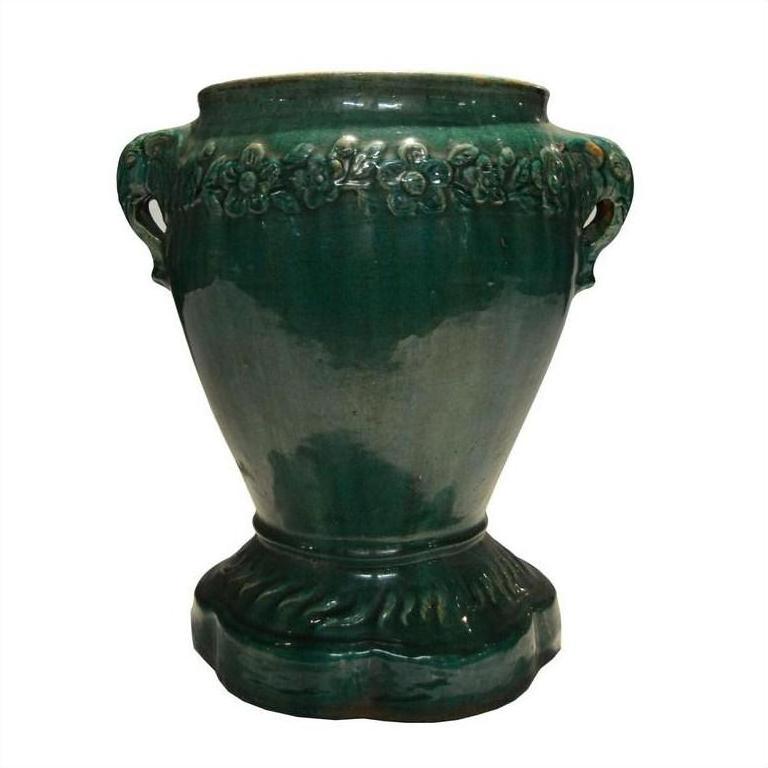 Green glazed ceramic Annamese garden seat with two handles and floral band near top, close-up view.
