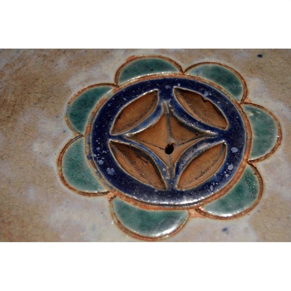 Green, blue, and brown glazed ceramic Annamese garden seat or side table with floral pattern and center hole.