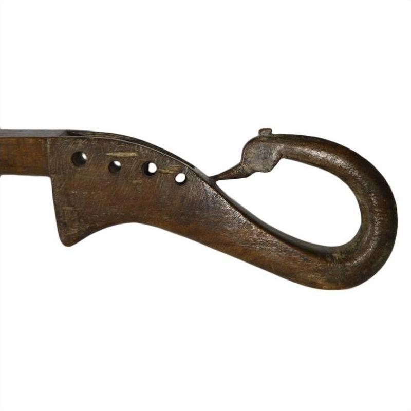 Close-up of a brown hand carved wooden Indian lute with four holes and a hook-shaped end on white background.