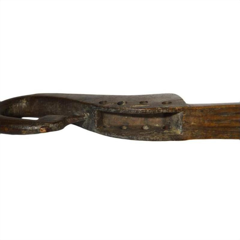 Close-up of a weathered wooden Indian lute with a curved, looped end and rustic details.