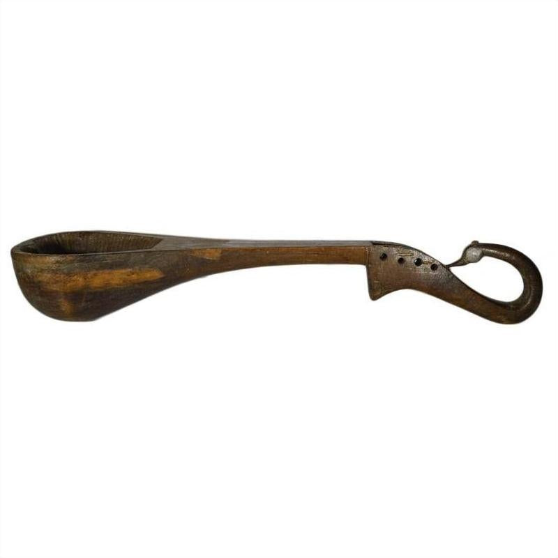 Brown hand-carved wooden Indian lute with deep bowl, curved handle, decorative holes, and hooked end for hanging.