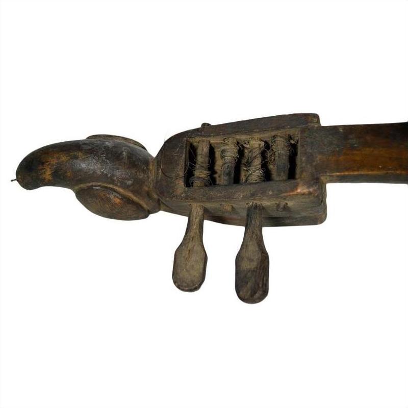 Brown wooden hand-carved Indian lute or sitar with animal head design, two tuning pegs, and visible strings, close-up.