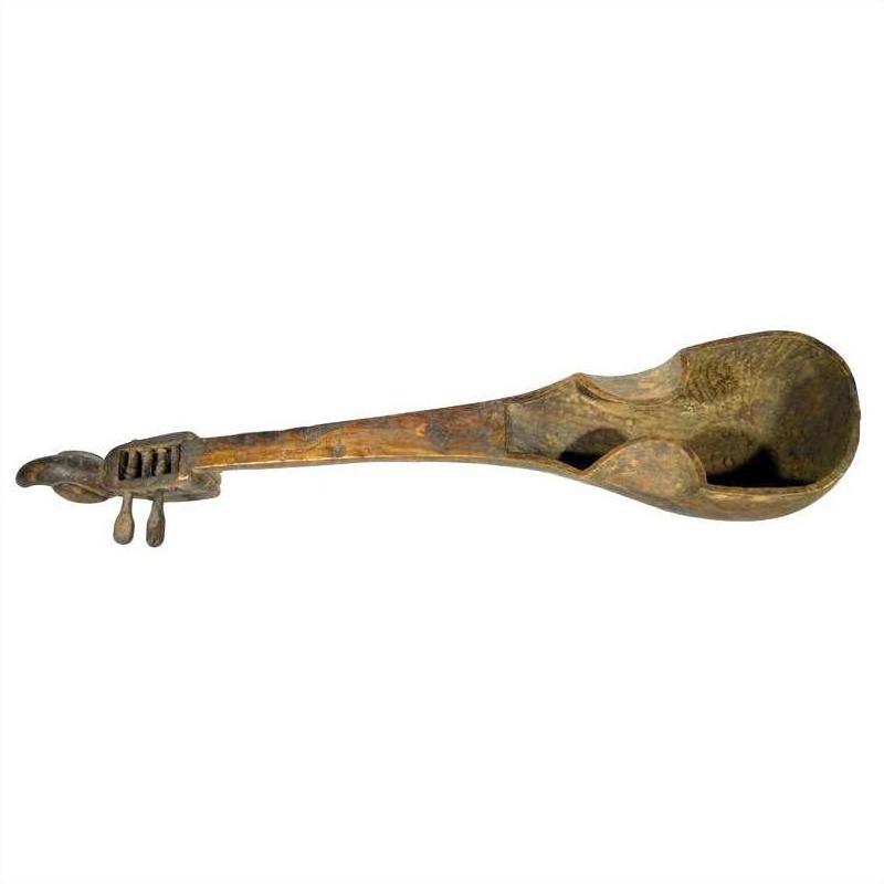 Close-up of an antique hand-carved wood Indian lute sitar ladle with detailed scrollwork and tuning pegs on the handle.