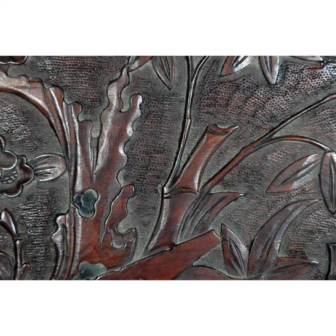 Close-up of antique lacquered rosewood wall plaque with hand-carved leaves and branches details.