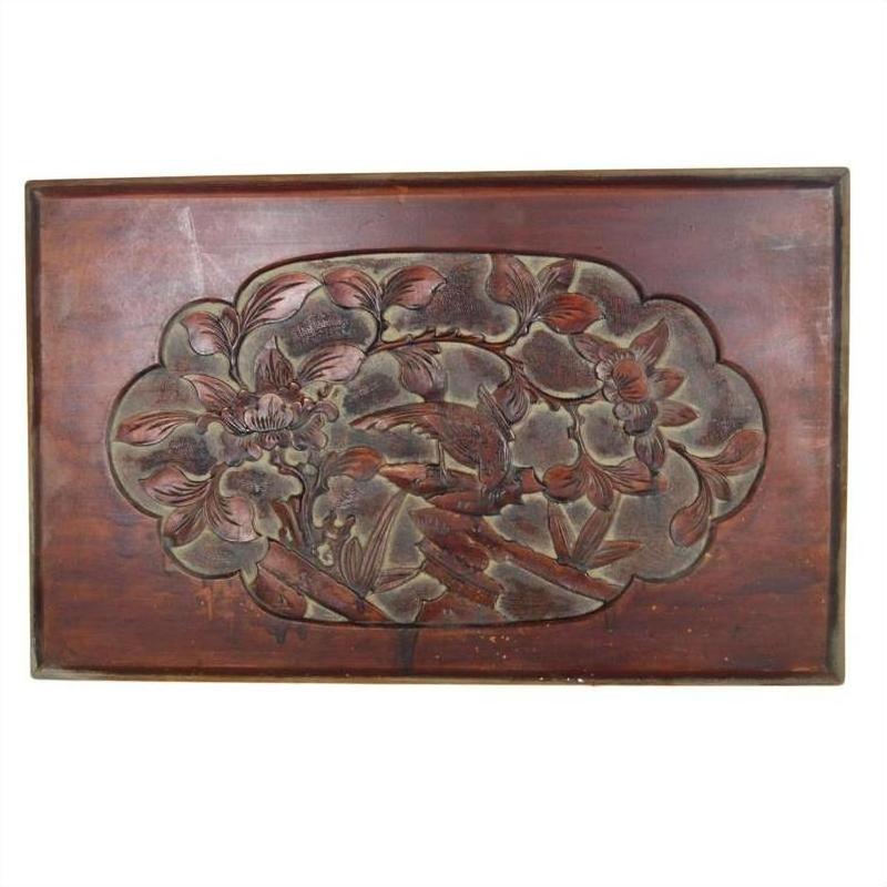 Close-up of dark red lacquered rosewood wall plaque with hand-carved central floral and leaf design.