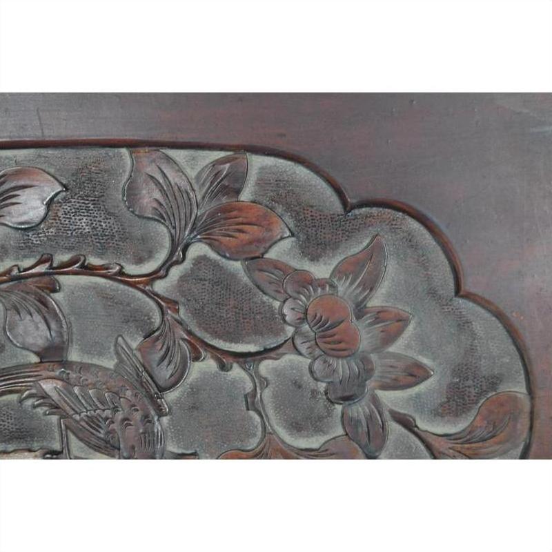Close-up of a dark rosewood wall plaque, hand-carved and lacquered, with 19th-century Chinese floral and leaf patterns.