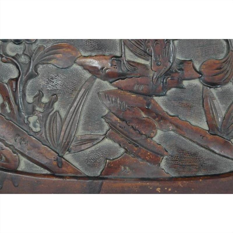 Close-up of intricate floral and leaf motifs carved into an antique rosewood wall plaque with a weathered lacquered finish.
