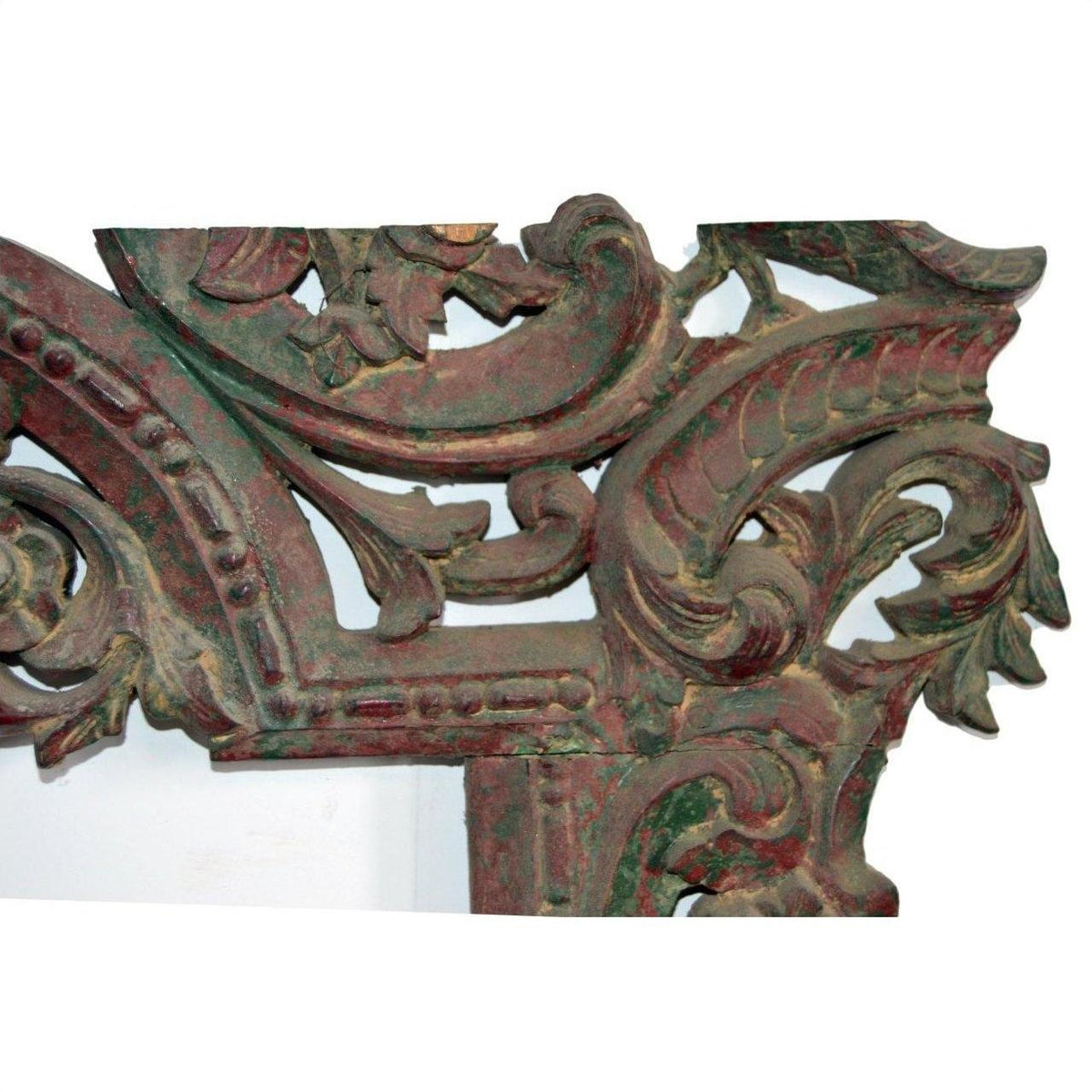 Close-up of antique reddish-green wood mirror frame with hand-carved swirling leaf patterns.