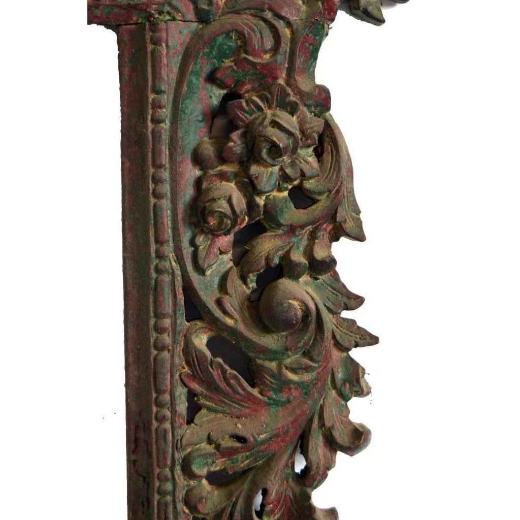 Close-up of weathered metal antique hand carved mirror frame with ornate floral and leaf designs.
