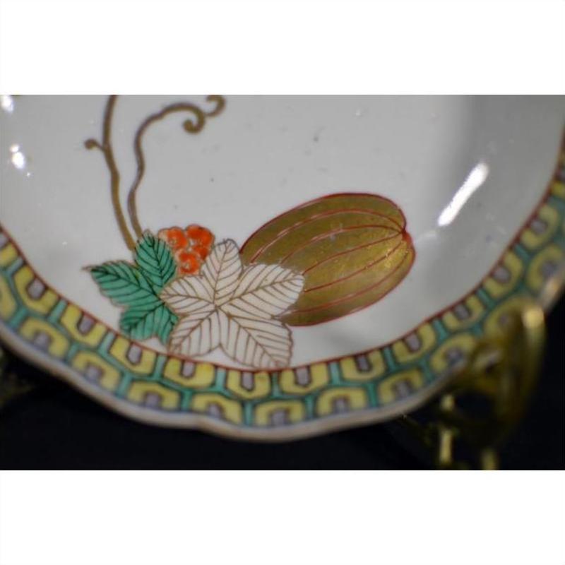 Close-up of antique hand painted Asian bowl with floral design and gold accents on a modern metal stand.