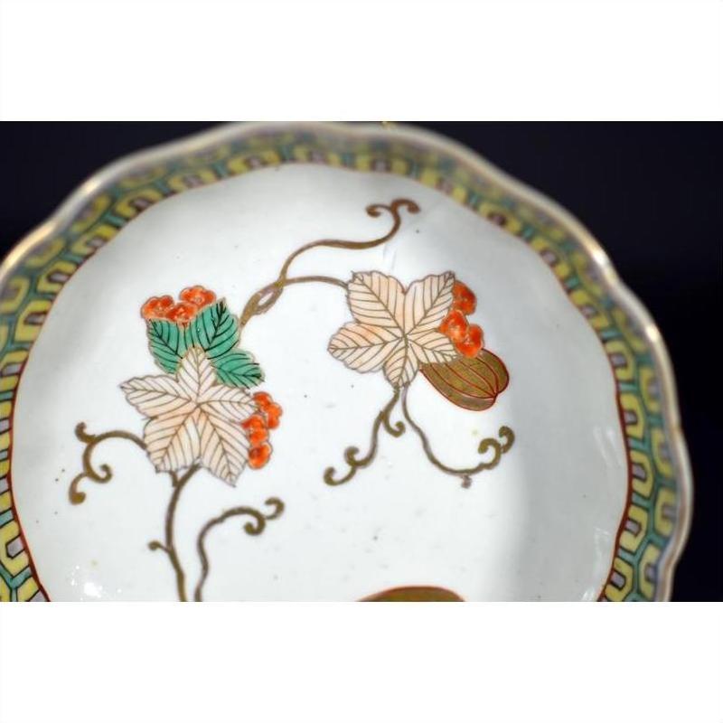 Close-up of white porcelain Asian bowl with red, green, and gold hand-painted floral and leaf patterns.