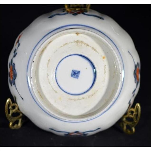 Close-up of ceramic bowl base with blue and red floral designs and a blue square mark in the center.