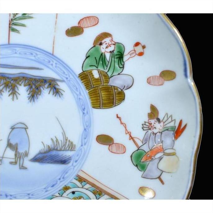 Close-up of antique hand painted Asian ceramic plate with figures in traditional attire holding objects beside barrels.