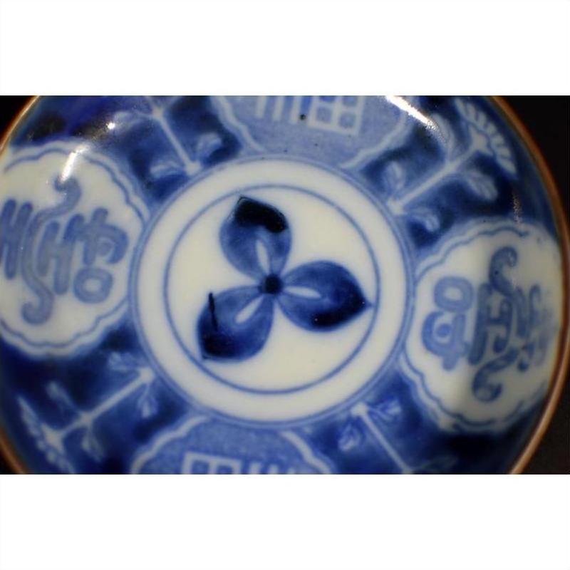 Close-up of blue and white hand painted ceramic plate with floral motif and bold abstract edge patterns.