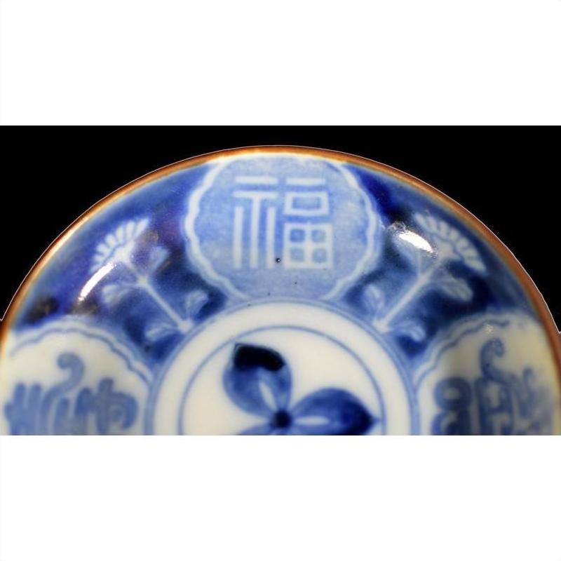 Close-up of blue and white ceramic plate with hand painted Chinese patterns and 福 (fortune) character.
