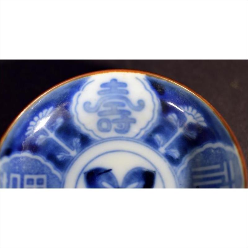 Close-up of blue and white ceramic Asian plate with hand painted decorative patterns and Chinese characters.