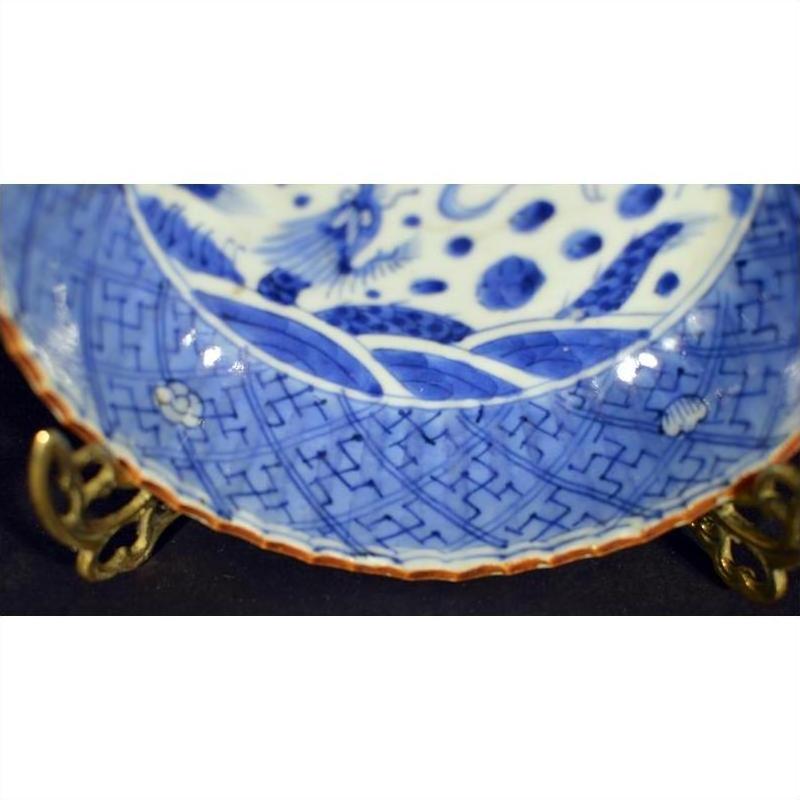 White porcelain Chinese bowl with hand painted decoration on ornate brass stand, close-up view.