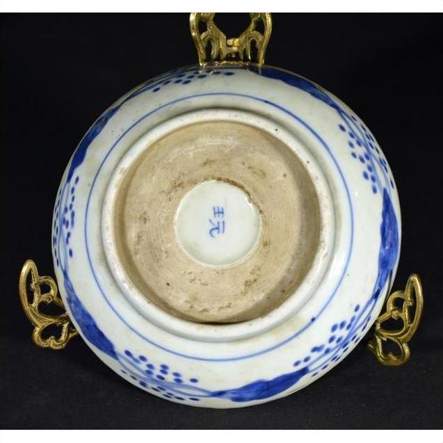 Close-up of the underside of an antique hand painted Chinese porcelain bowl with blue mark, on brass stand.