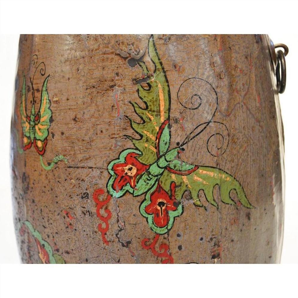 Close-up of brown ceramic antique Chinese drum with hand painted butterflies and swirling designs.