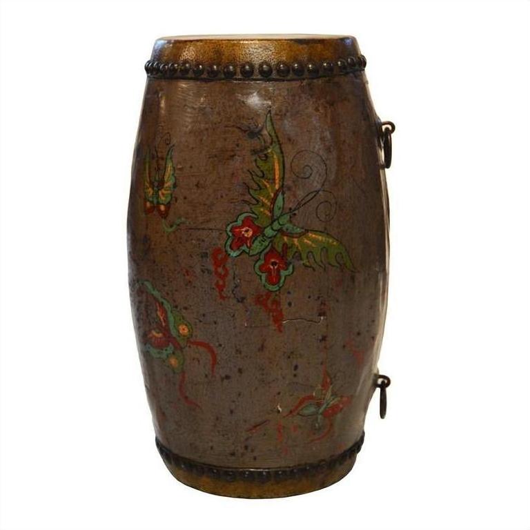 Brown hand-painted antique Chinese drum with green and red designs, metal studs along edges, close-up view.