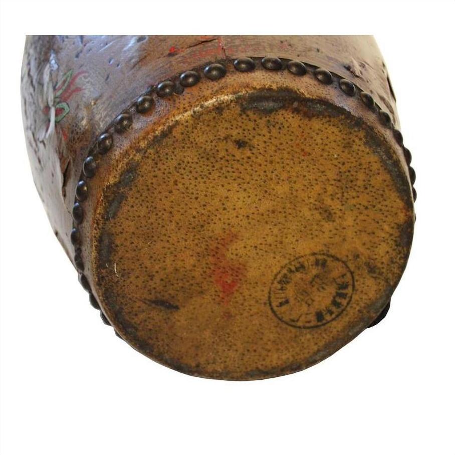 Close-up of red and brown painted ceramic drum base with stamp mark and decorative beading along edge.