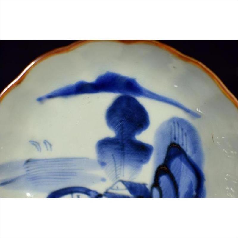 Close-up of blue and orange hand painted Chinese porcelain bowl with landscape and modern cloud motif.