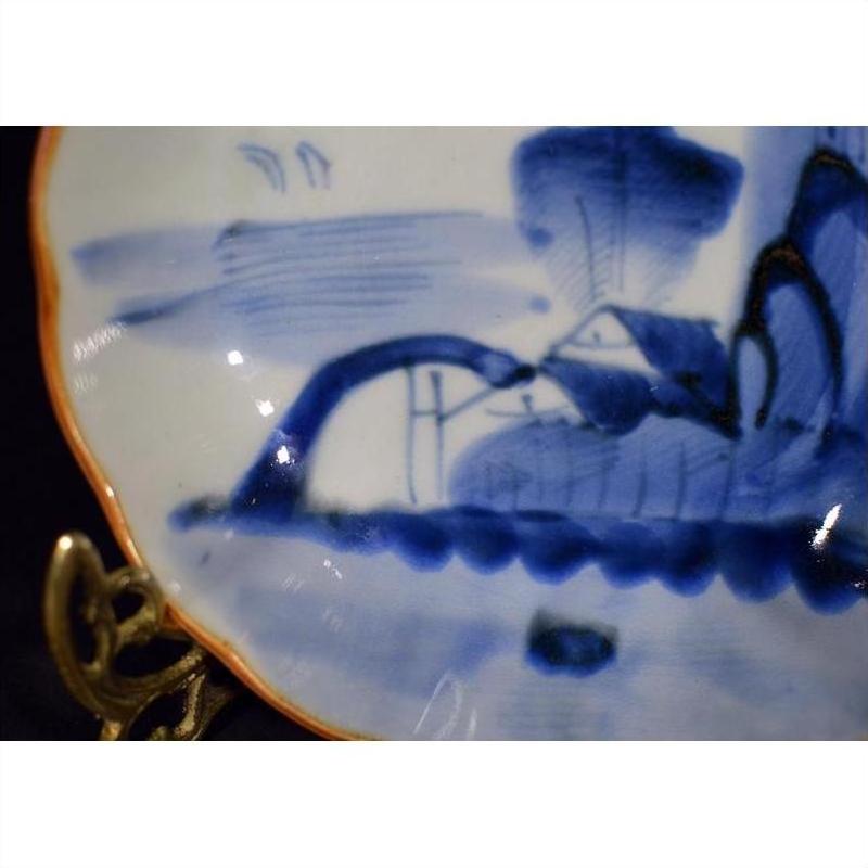 Close-up of blue and white hand painted Chinese porcelain bowl with water, hills, and birds scene.