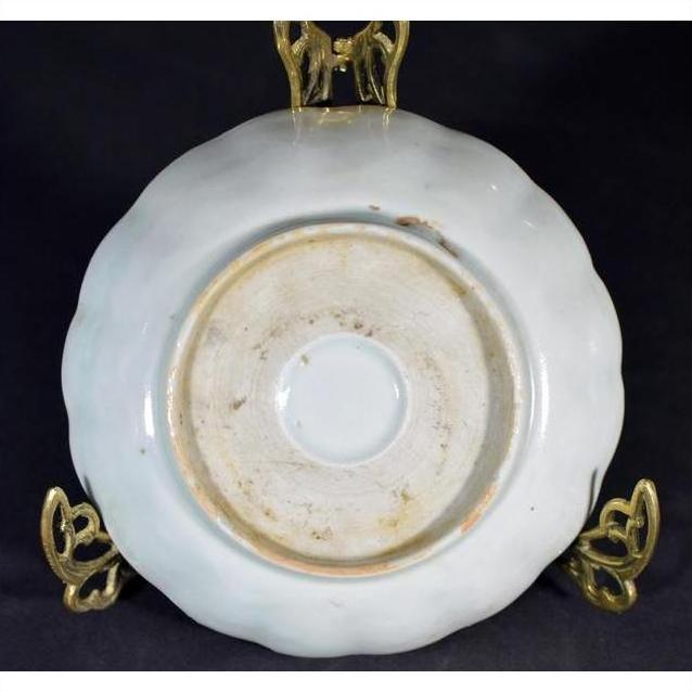 Close-up of the underside of an antique hand painted Chinese porcelain bowl on a gold stand, black background.