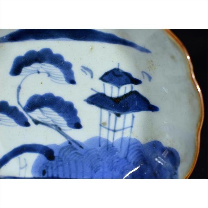 Blue and white porcelain plate with hand painted Chinese landscape, trees, and pagoda design.