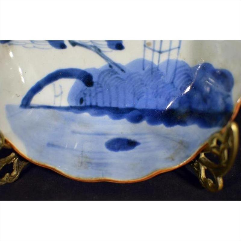 Close-up of a hand painted antique Chinese porcelain plate with colorful designs on an ornate metal stand.