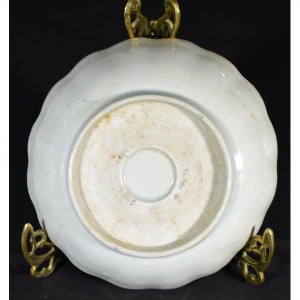 Close-up of the underside of an antique hand-painted Chinese porcelain plate on an ornate brass stand.