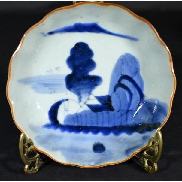 Close-up of blue hand-painted Chinese porcelain plate with brown rim, displayed on a decorative stand.