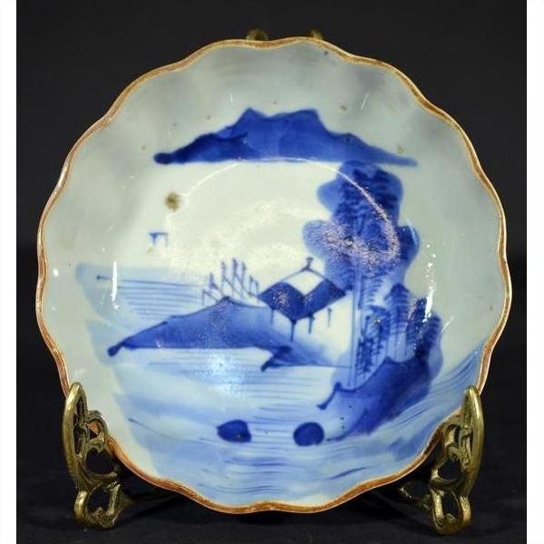 Blue and white hand painted Chinese porcelain plate with landscape design on decorative metal stand.