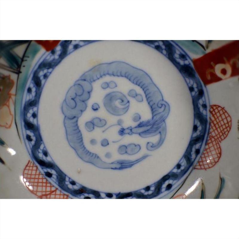 Close-up of antique Japanese Imari porcelain bowl, hand painted with blue dragon motif and red, blue rim accents.