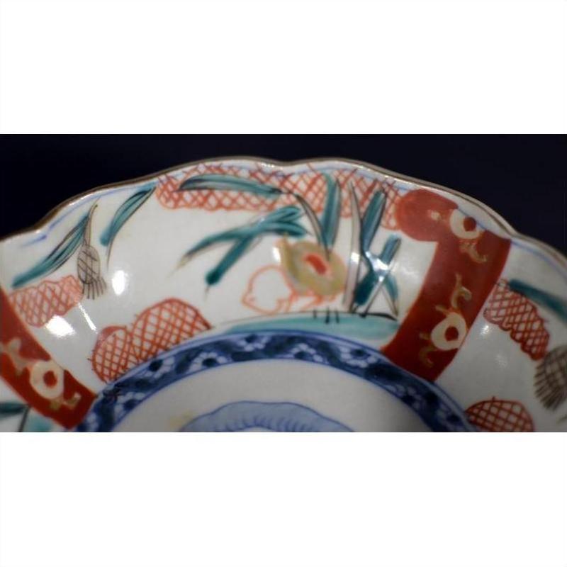 Close-up of red, blue, and green hand painted porcelain Japanese Imari bowl with intricate decorative motifs.