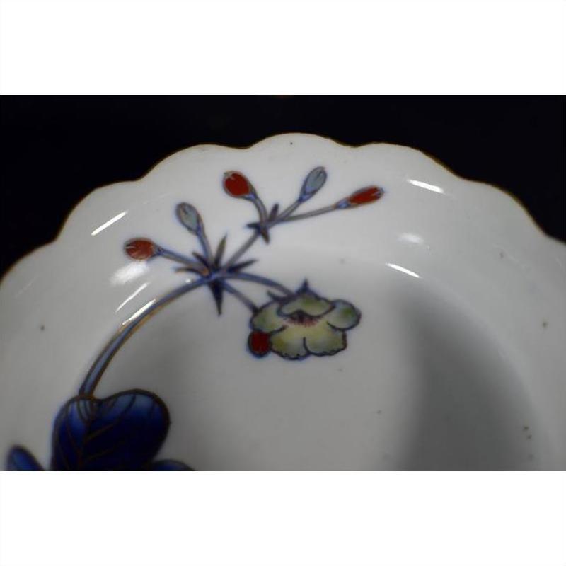 Close-up of four multicolored porcelain Japanese Imari bowls with scalloped edges and floral rim designs.