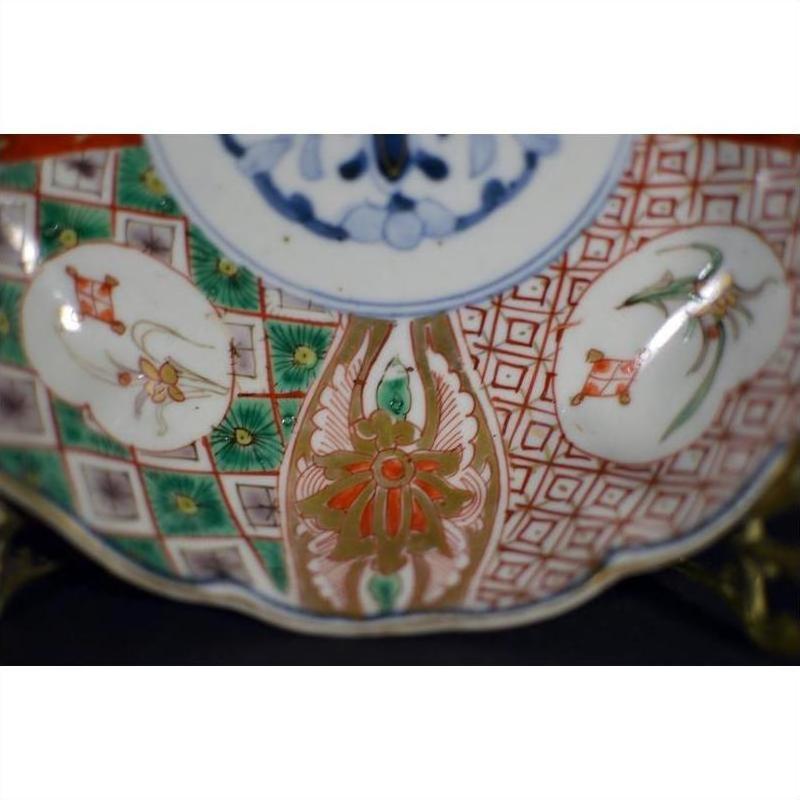 Close-up of antique Japanese Imari porcelain bowl with red, green, and gold hand-painted floral patterns.