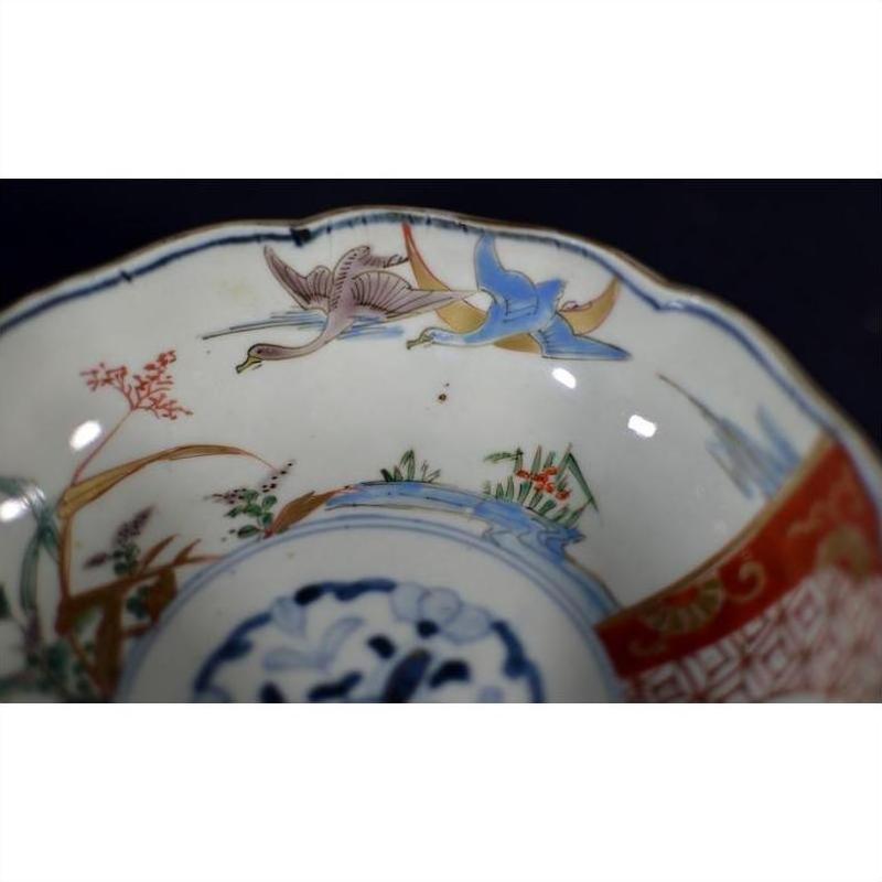 Close-up of antique Japanese Imari porcelain bowl, hand painted with blue, red, green and gold birds and landscapes.