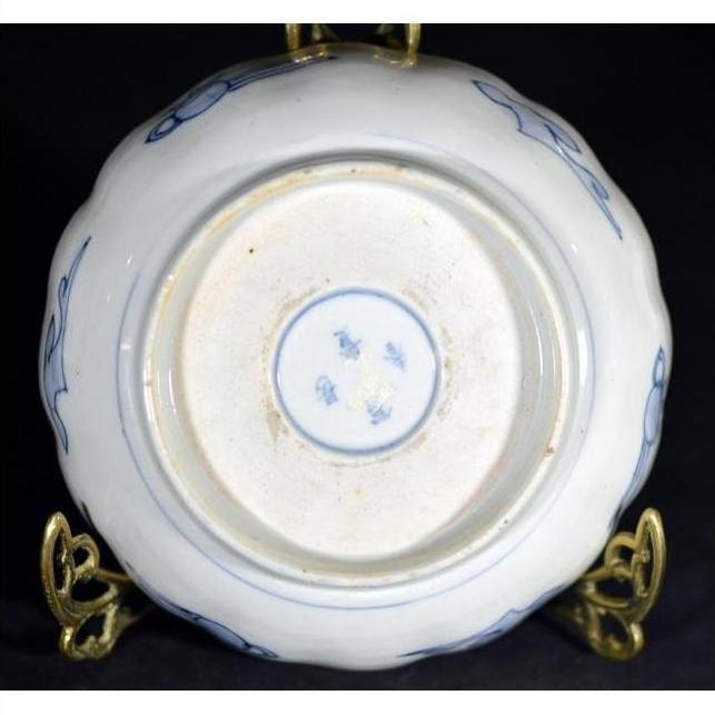 Blue and white porcelain bowl underside with hand-painted designs, shown on a brass stand.