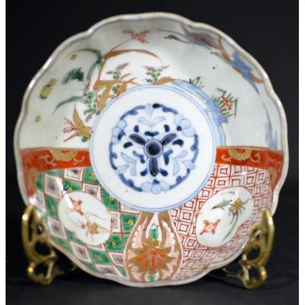 Close-up of an antique Japanese Imari porcelain bowl with vibrant hand-painted patterns on a brass stand.