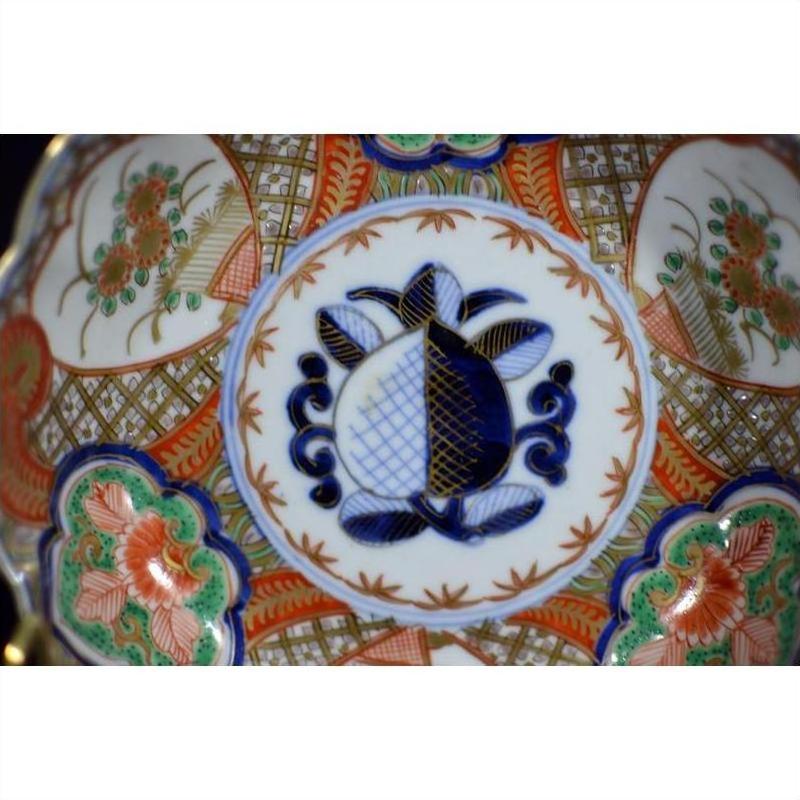 Close-up of blue, red, and green hand painted floral patterns on antique Japanese Imari porcelain bowl.