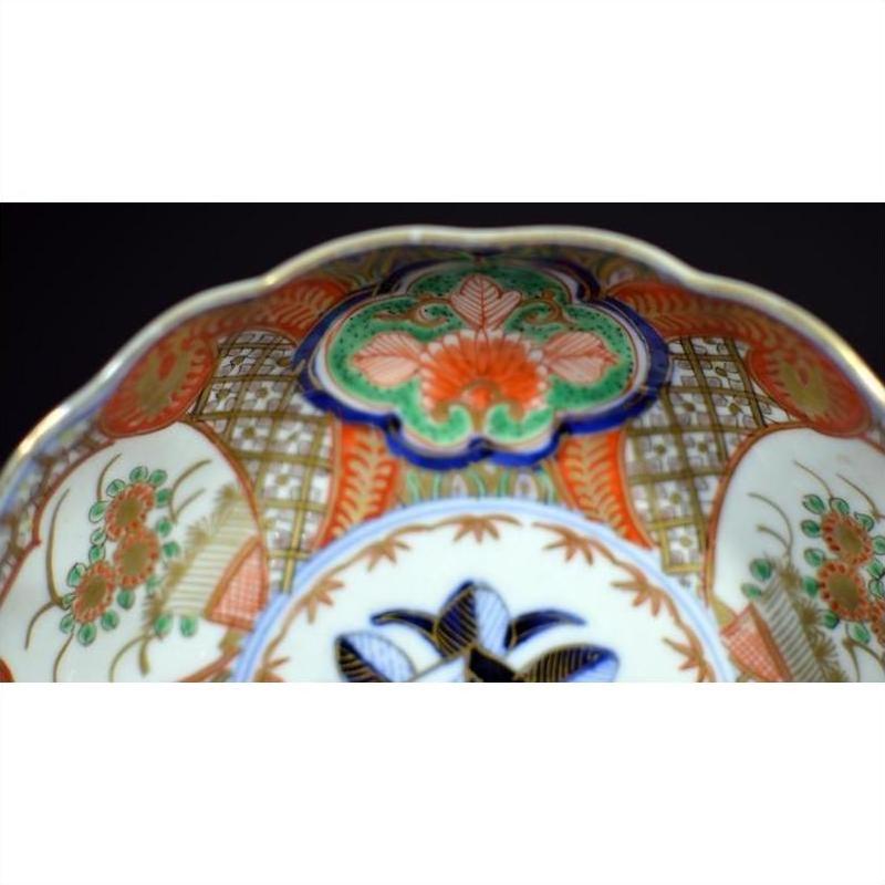Close-up of antique Japanese Imari porcelain bowl with hand painted intricate red, green, blue, and gold patterns.