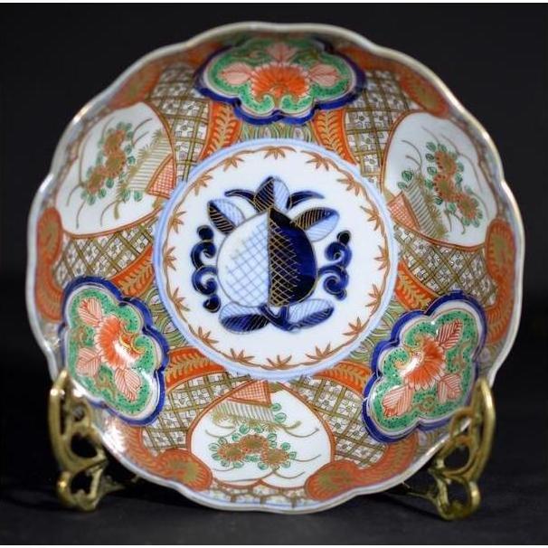 Close-up of antique Japanese Imari porcelain bowl with red, green, and blue floral patterns and central blue fish.