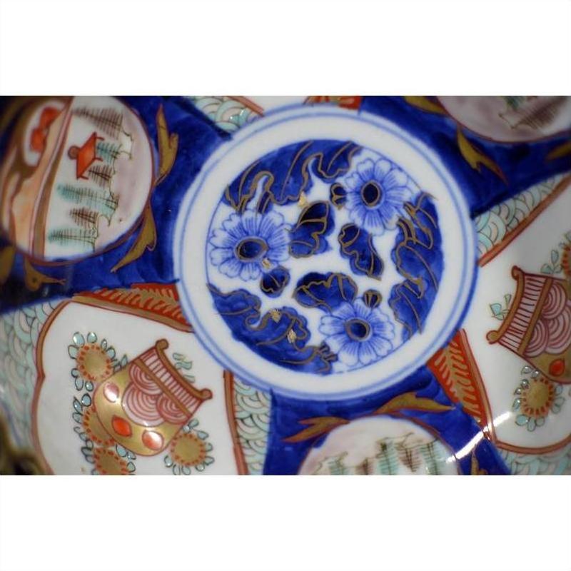 Blue, white, orange, and gold porcelain Imari bowl with ornate hand-painted circular designs, close-up view.