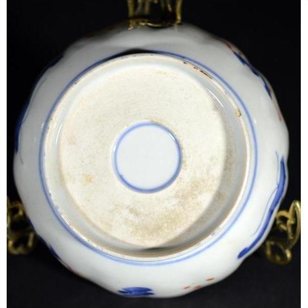 Close-up of the bottom of an antique hand painted Japanese Imari porcelain bowl with blue mark on metal stand.